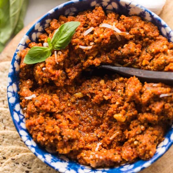 sun dried tomato pesto in a bowl topped with basil