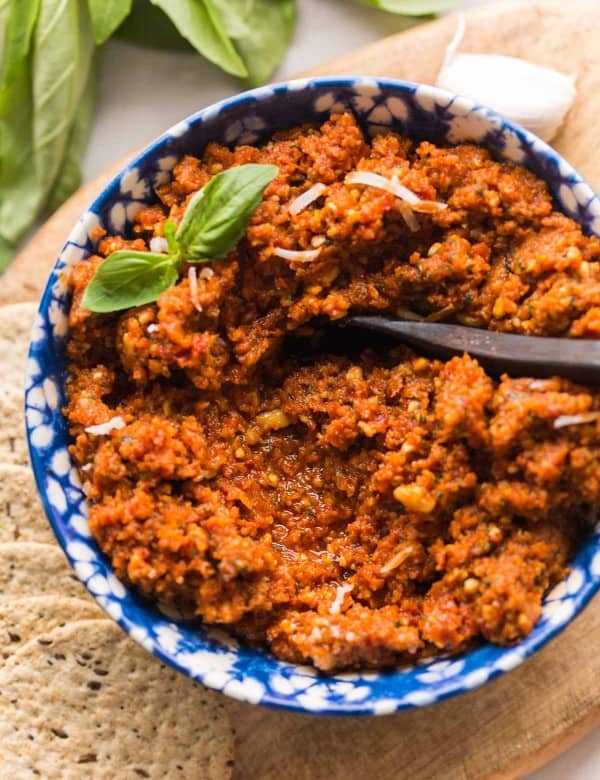 sun dried tomato pesto in a bowl topped with basil