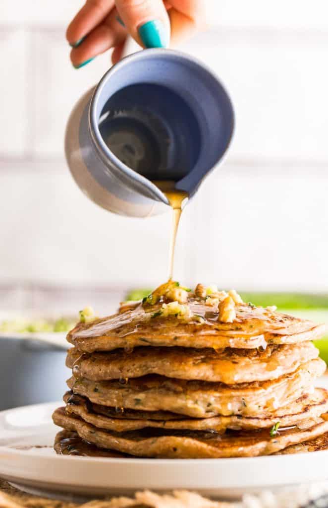 Zucchini Bread Pancakes stacked with syrup pouring over the top