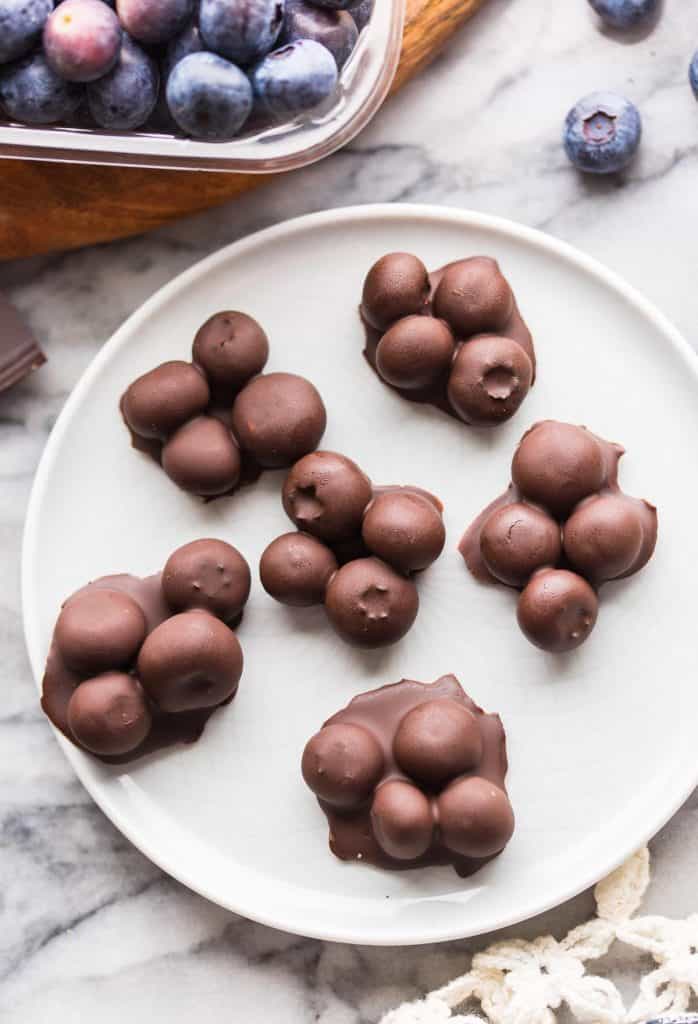 six small clusters of Chocolate Covered Blueberries on a small plate