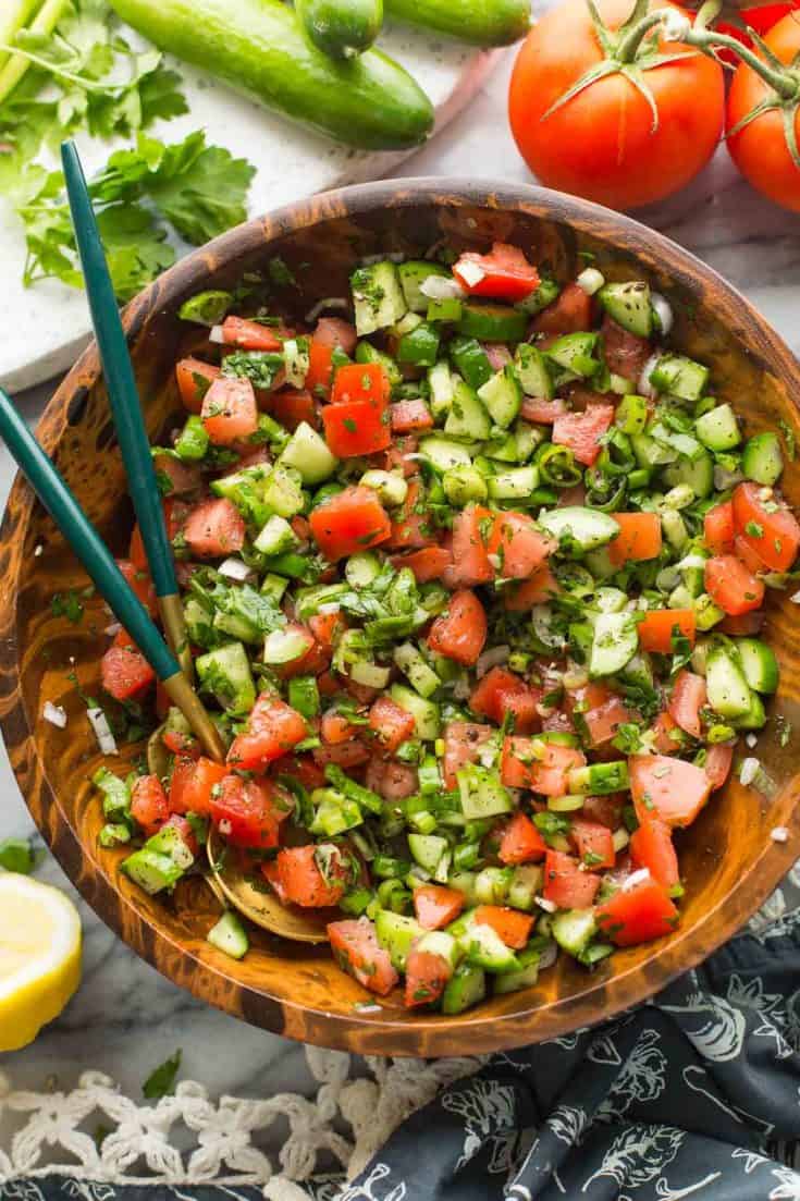 shirazi salad in a wooden salad bowl with a couple of salad tongs