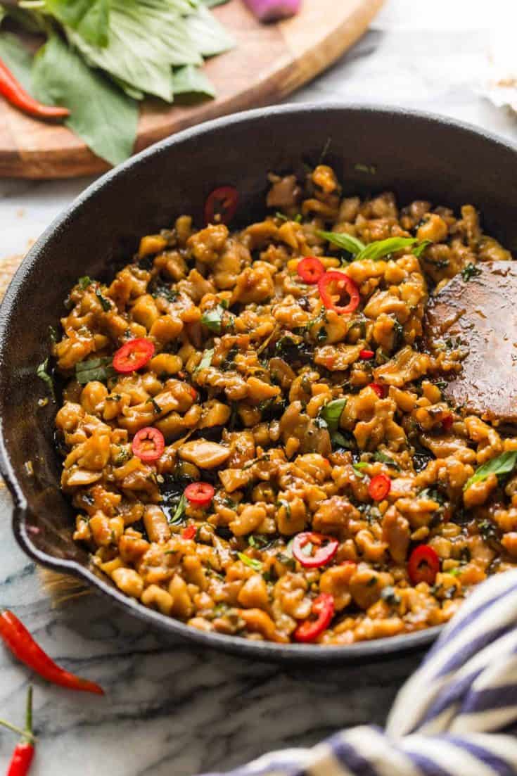 Pad Krapow Gai in a cast iron skillet with a wooden spoon