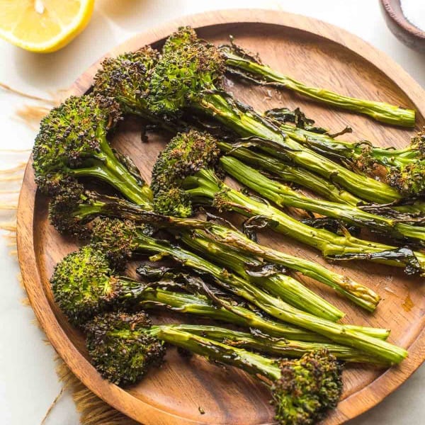 roasted tenderstem broccoli on a plate with lemons on the side