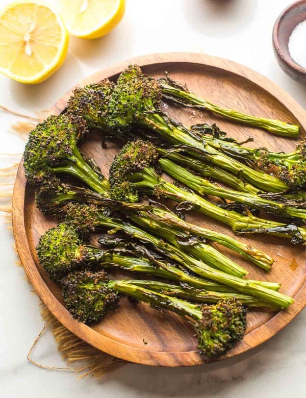 roasted tenderstem broccoli on a plate with lemons on the side