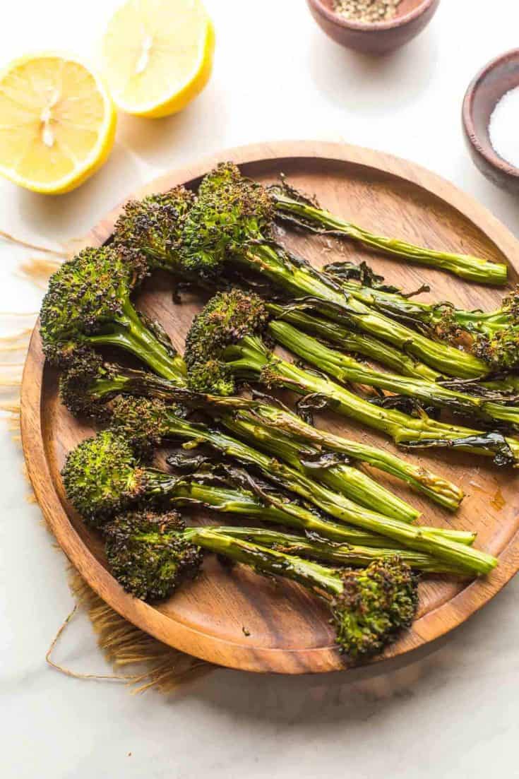 roasted tenderstem broccoli on a plate with lemons on the side