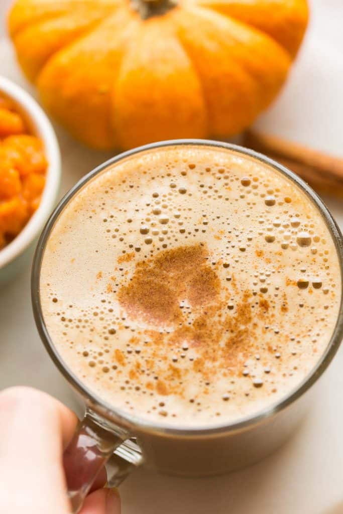 hand pick up a mug of Dairy Free Pumpkin Spice Latte 