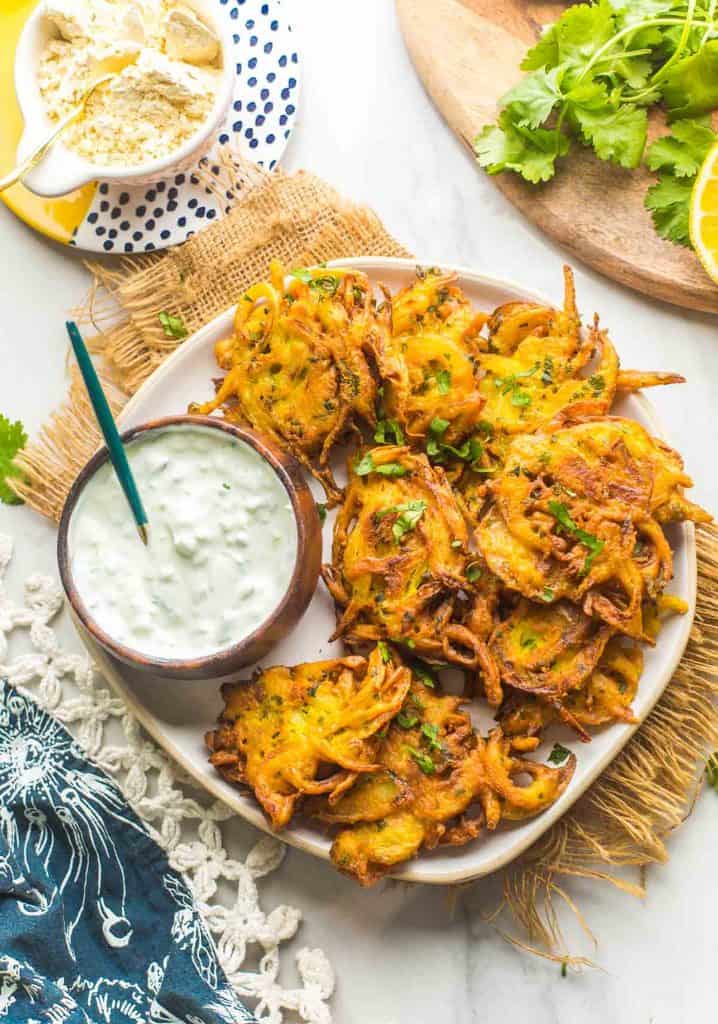 onion bhajis on a plate with a cucumber yoghurt dip on the side