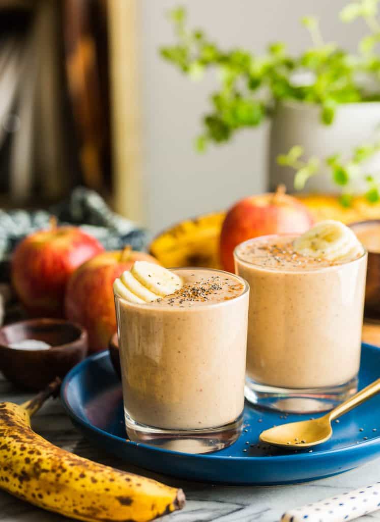 Apple Banana Smoothie glasses on a plate topped with chia seeds and banana on the side