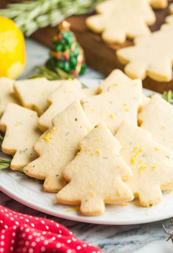 Rosemary Lemon Christmas Tree Cookies on a plate with fresh rosemary sprigs and topped with lemon zest
