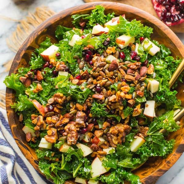 Winter Kale Salad filled with apples, toasted walnuts and pumpkin seeds, pomegranate in a bowl