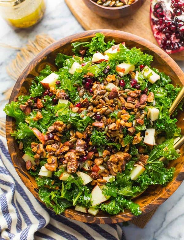 Winter Kale Salad filled with apples, toasted walnuts and pumpkin seeds, pomegranate in a bowl