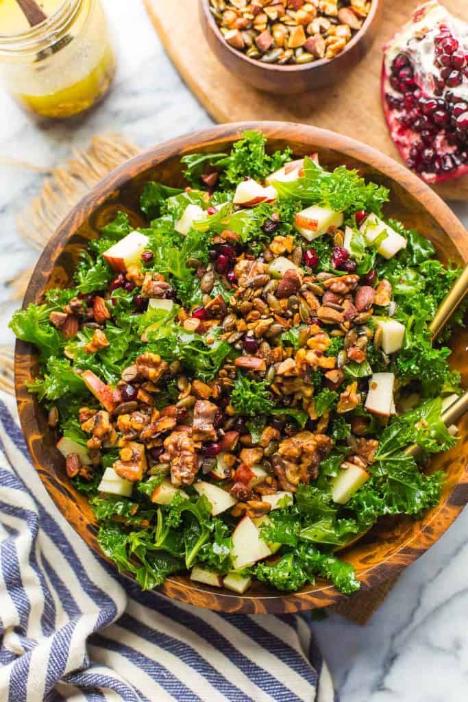 Winter Kale Salad filled with apples, toasted walnuts and pumpkin seeds, pomegranate in a bowl