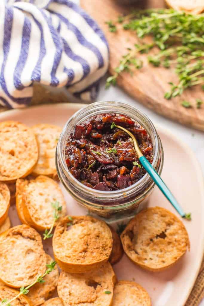Bacon Jam  in a jar with a serving spoon and crackers on the side