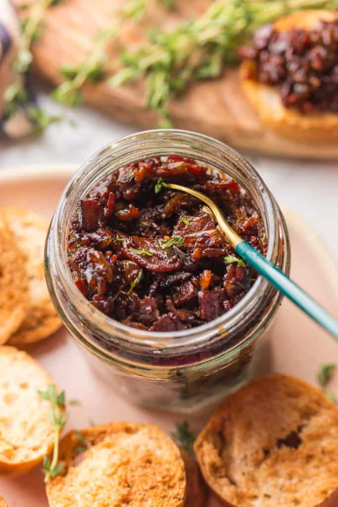 Bacon Jam in a jar with fresh thyme and crackers on the side