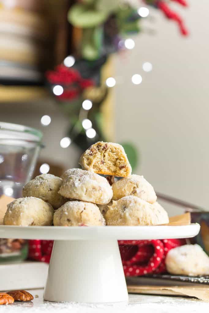 a pile of pecan meltaways piled on a platter with a bite taken out of the top cookie