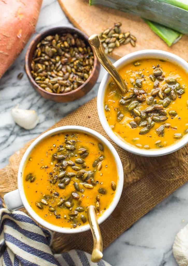 two bowls of Leek and Sweet Potato Soup topped with roasted pumpkin seeds