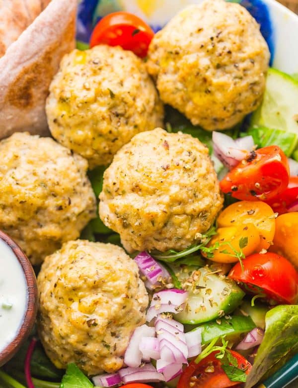 homemade Greek-Chicken-Meatballs in a salad bowl with chopped red onion, cucumber and tomatoes