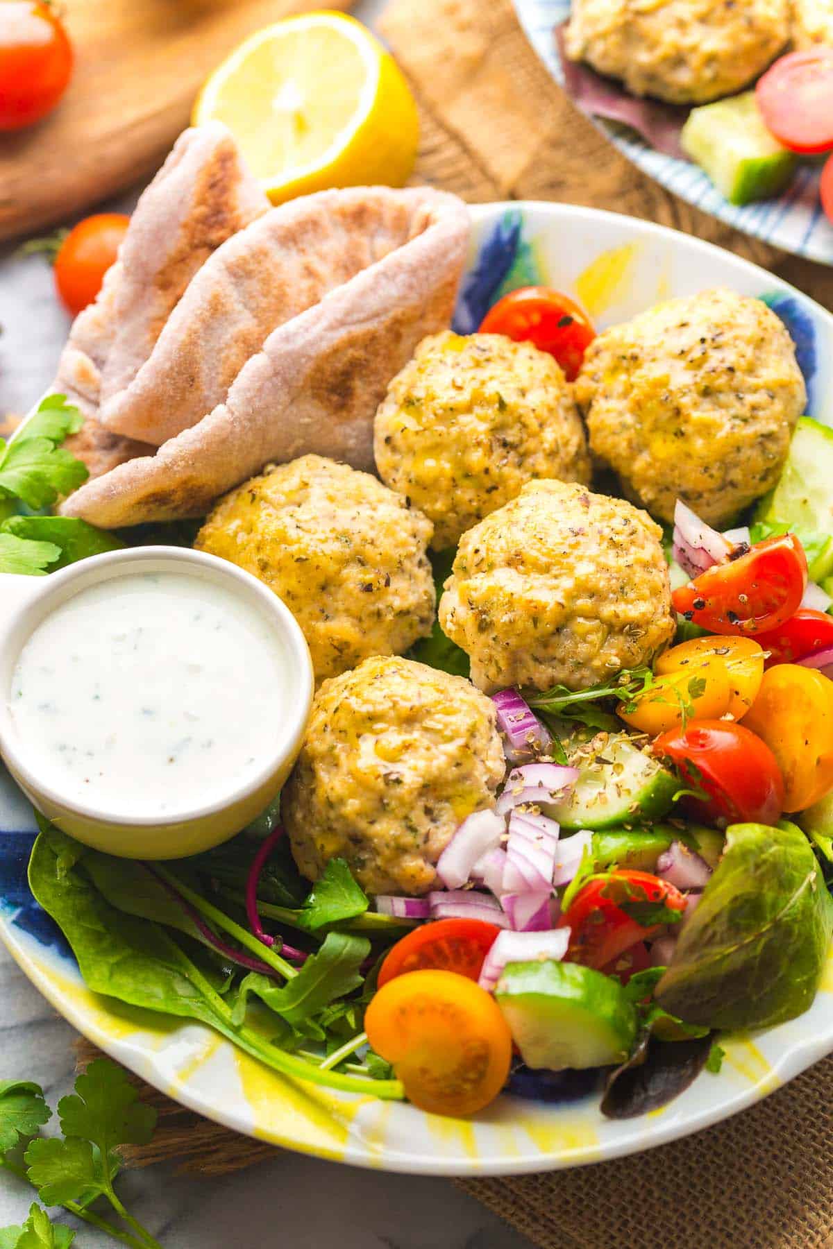 Baked Greek Chicken Meatballs in a salad with flatbread and tzatziki
