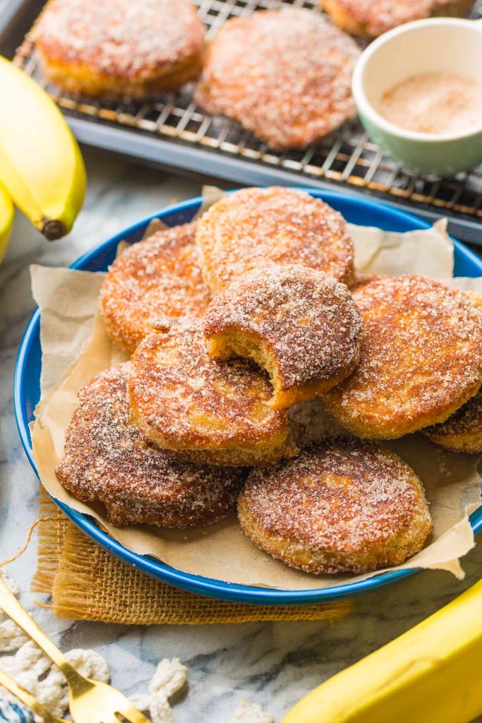 homemade banana fritters on a plate with a bite taken out of one