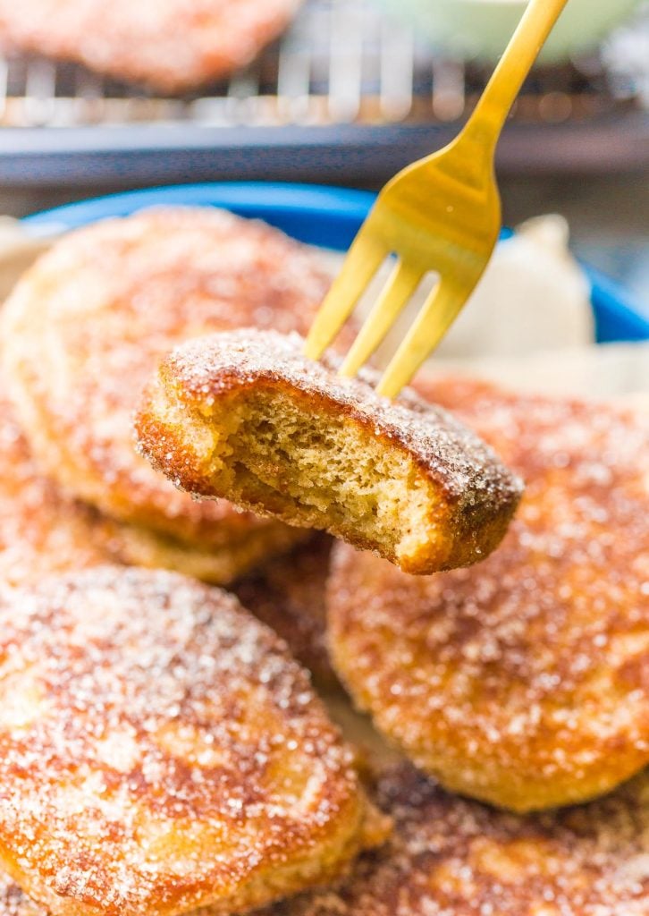 a fork holding up a banana fritter with a bite taken out