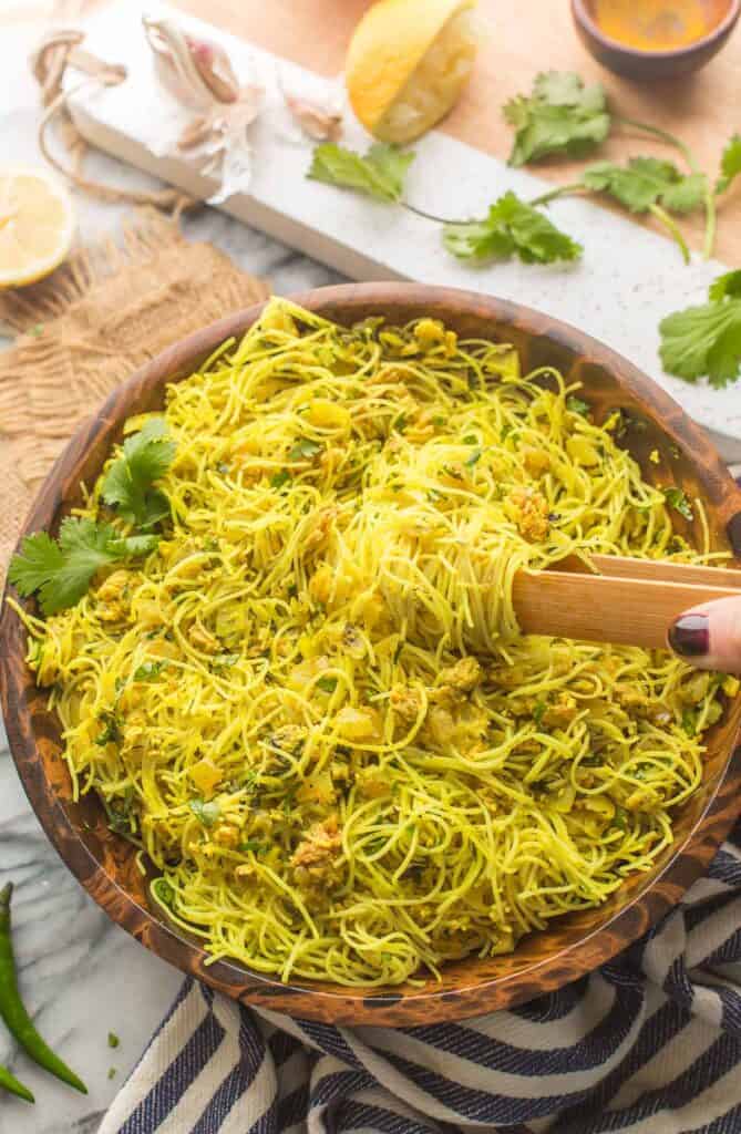 Bangladesh style Fried Vermicelli Noodles in a bowl with serving spoons topped with chopped cilantro with tongs