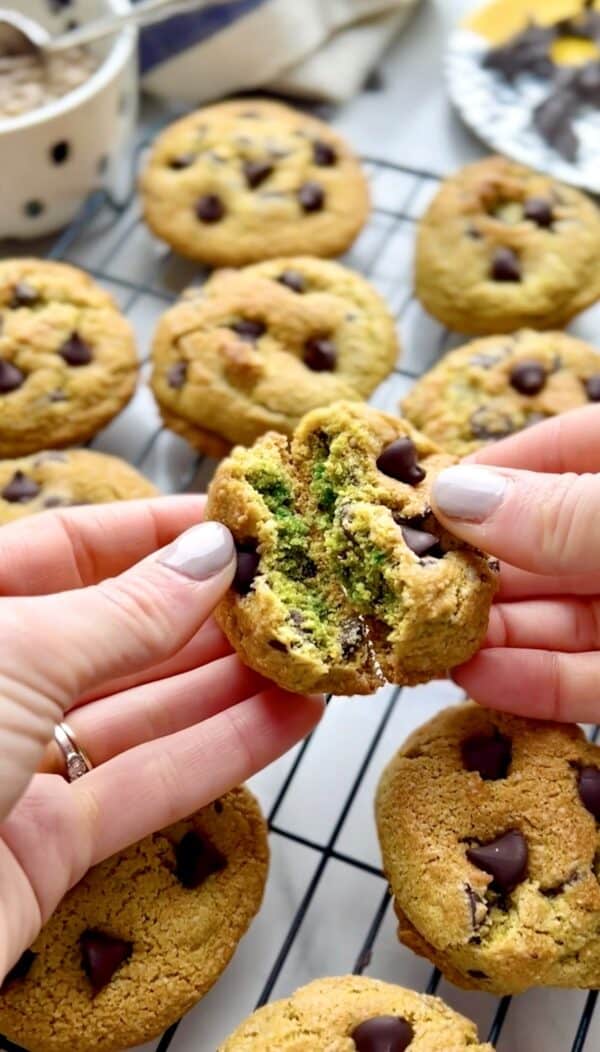 a-pair-of-hands-breaking-a-sunflower-cookie-in-half-showing-off-its-green-inside-