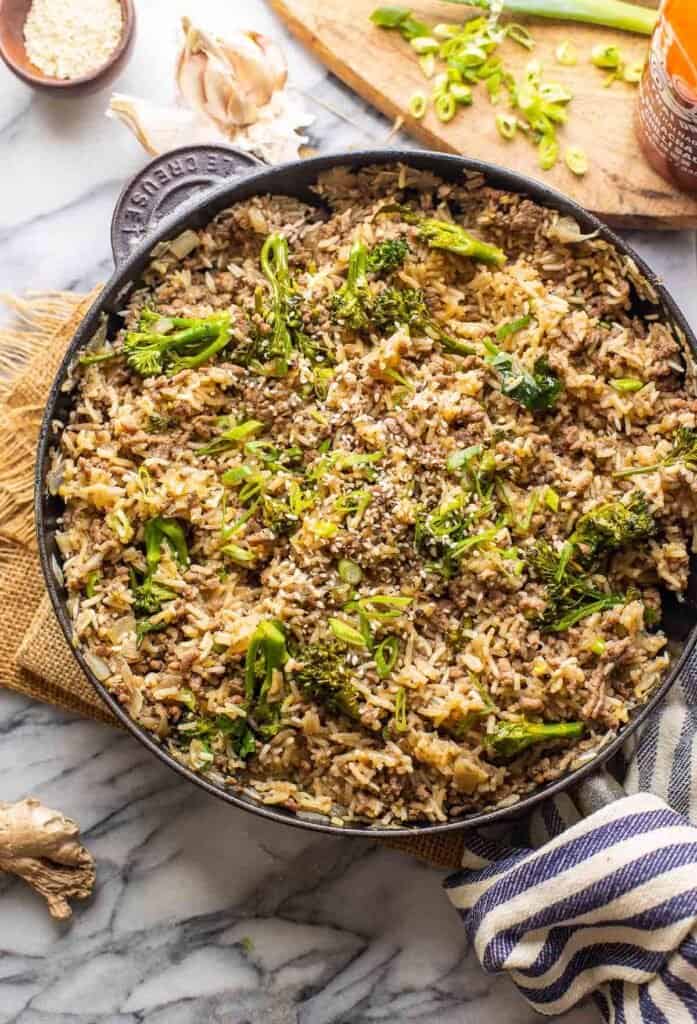 Ground Beef with Broccoli with Rice in a cast iron skillet topped with sliced green onions 