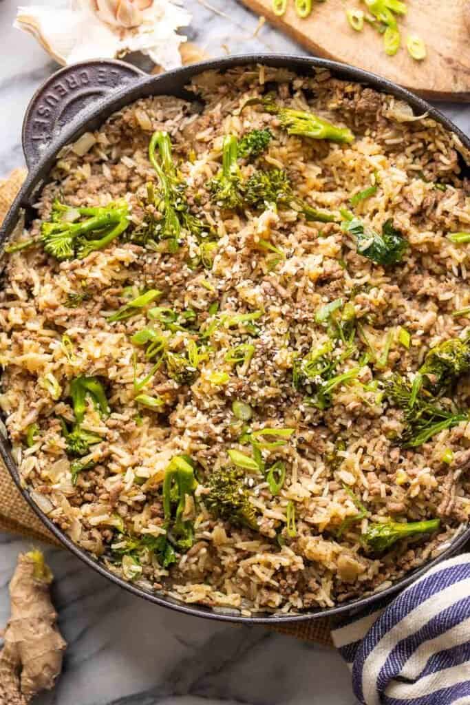 Ground Beef and Broccoli with Rice in a cast iron skillet topped with sliced green onions and sesame seeds