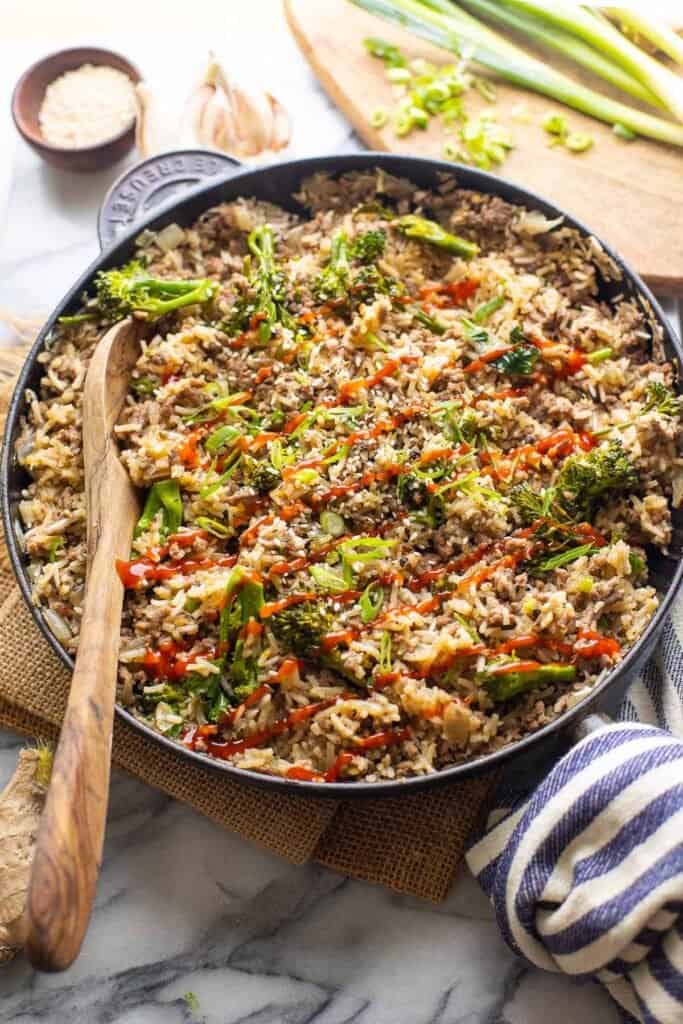 Ground Beef and Broccoli with Rice in a cast iron skillet topped with sriracha 