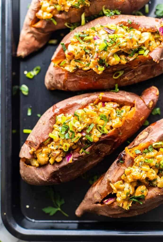 Stuffed sweet potatoes filled with a spicy chickpea Mayo salad on a baking sheet