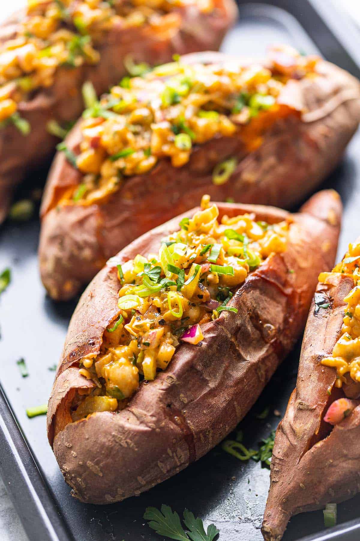 Smashed chickpea stuffed sweet potatoes topped with green onions