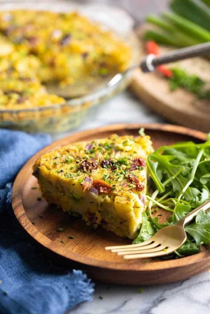 a slice of crustless vegan quiche with a side salad