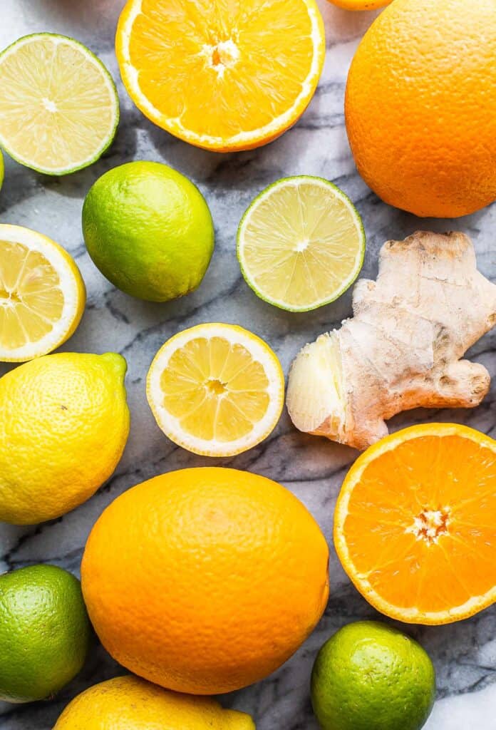 oranges, lemons, limes and piece of ginger on a counter top