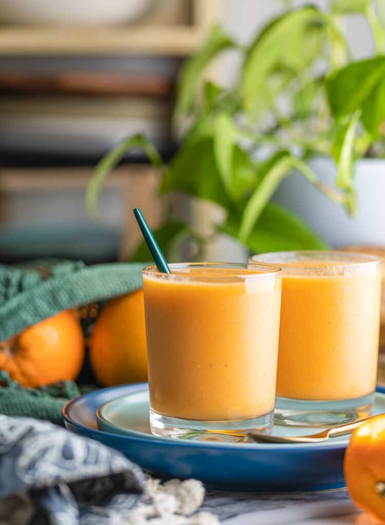 two glassed of an orange creamsicle smoothie on a plate