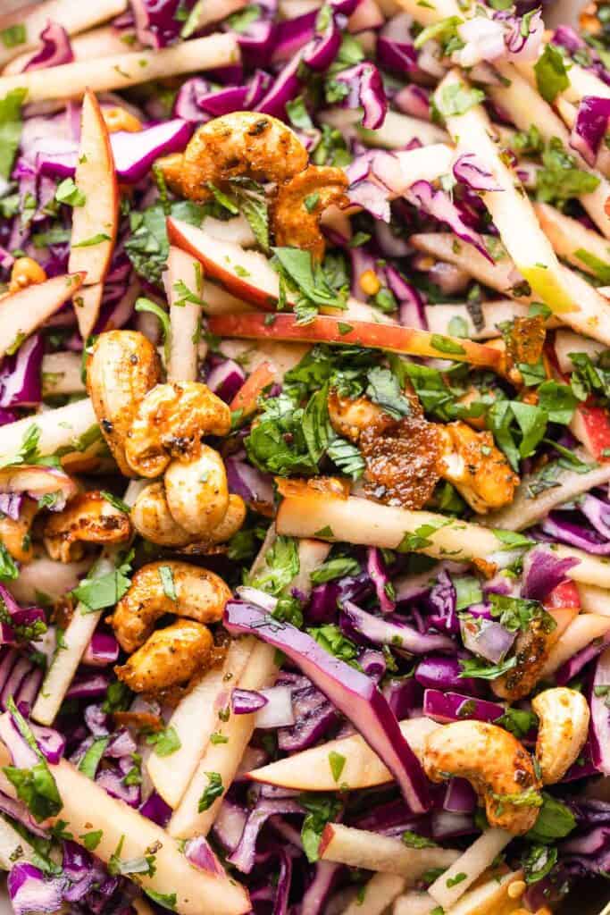 Apple and Red Cabbage Salad pictured up close: maple and chilli cashews mixed in with fresh herbs, apple sliced and cabbage