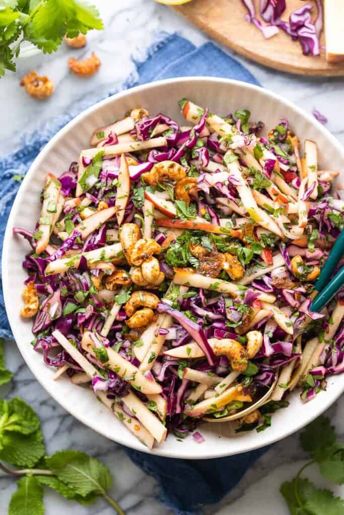 red cabbage salad in a dish with serving spoons on the side