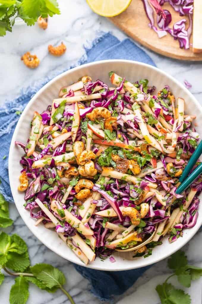 Apple and Red Cabbage Salad in a bowl with serving tongs