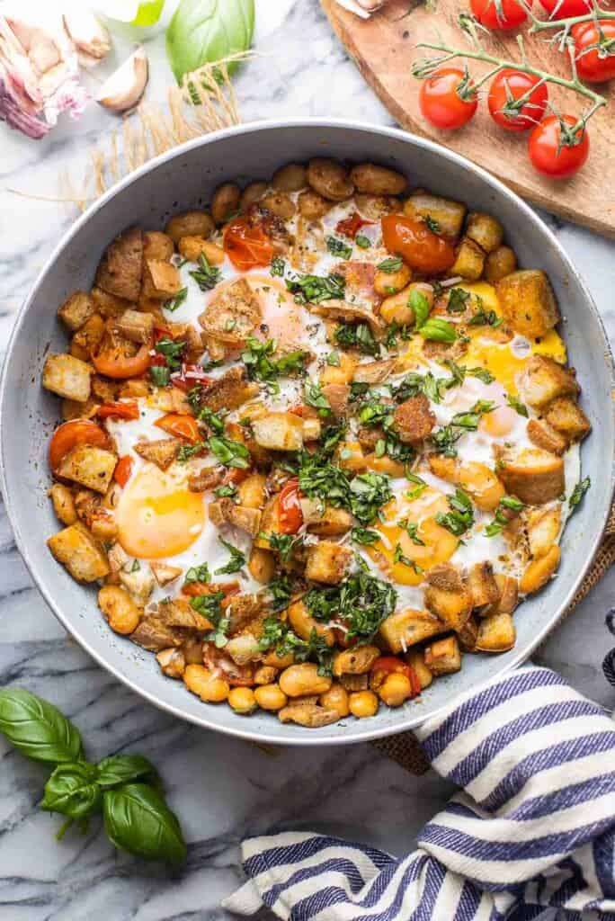 Burst Cherry Tomatoes & White Bean Egg Skillet on a counter top surrounded by the fresh ingredients