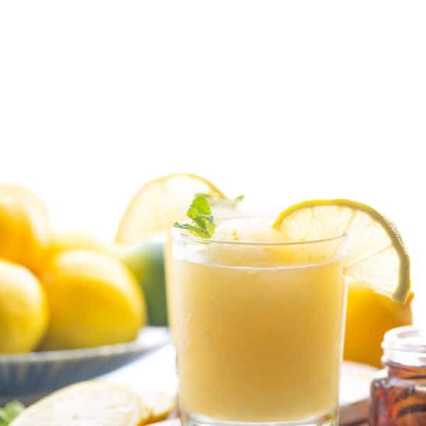 frozen lemonade in a glass garnished with mint leaves and a lemon slice