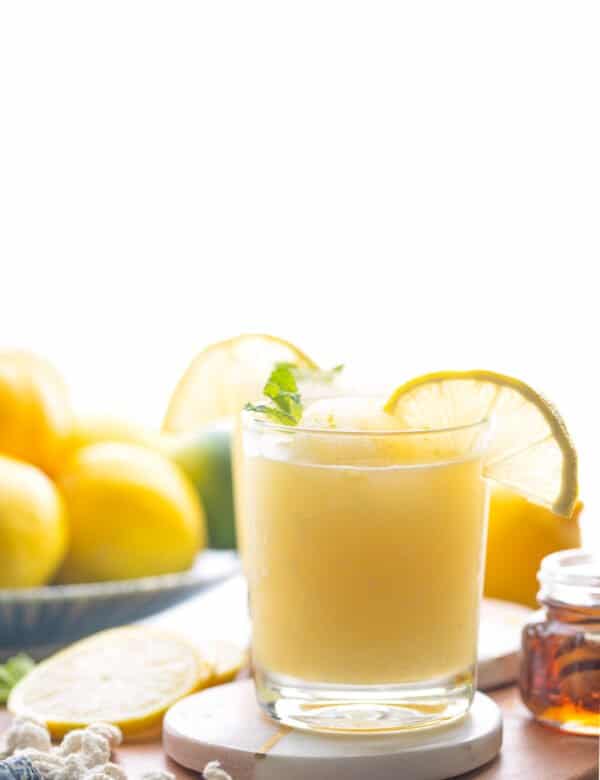 frozen lemonade in a glass garnished with mint leaves and a lemon slice