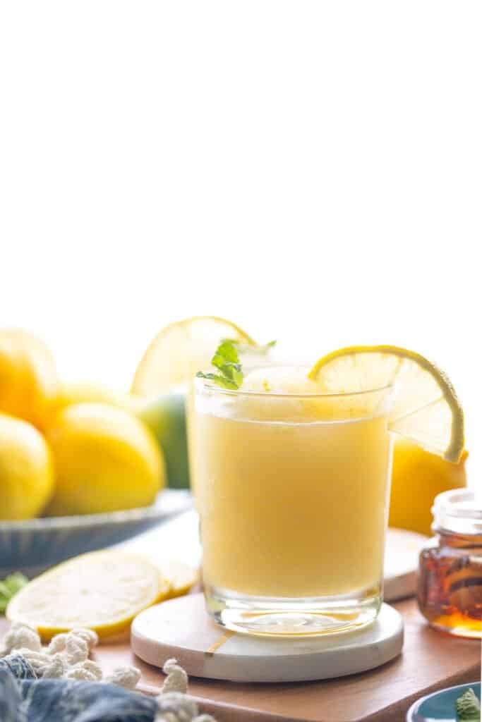 a glass of frozen lemonade garnish with a lemon slice and mint leaf