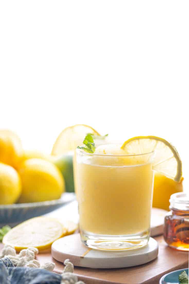 frozen lemonade in a glass garnished with mint leaves and a lemon slice