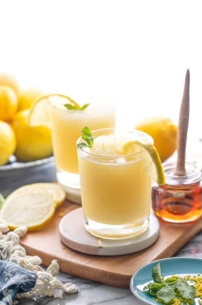 frozen lemonade glasses in front of a bowl of lemons and a side of maple syrup