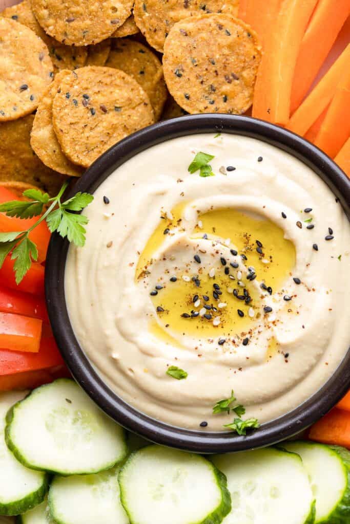 homemade hummus topped with olive oil and za'atar spice on a veggie platter
