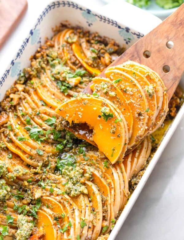 a helping of roasted butternut squash rounds in pesto on a serving spoon