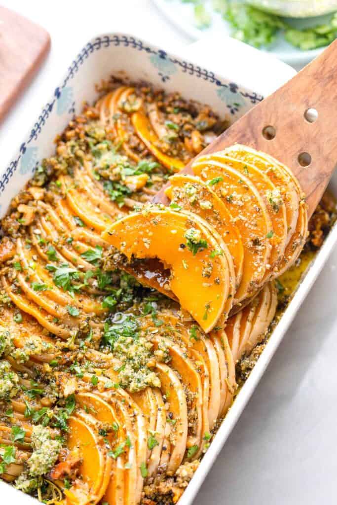 a helping of roasted butternut squash slices in pesto on a serving spoon