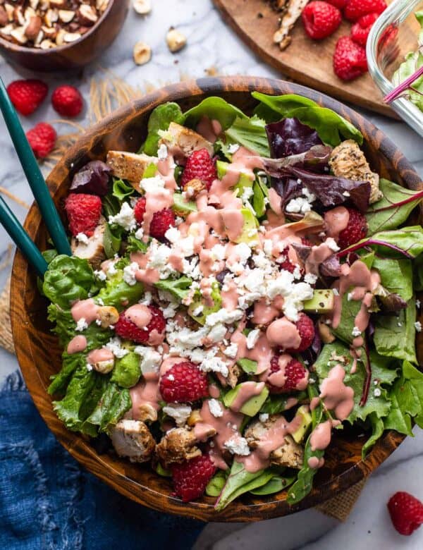 raspberry salad with chopped chicken, avocado, hazelnut and feta with a raspberry dressing on top
