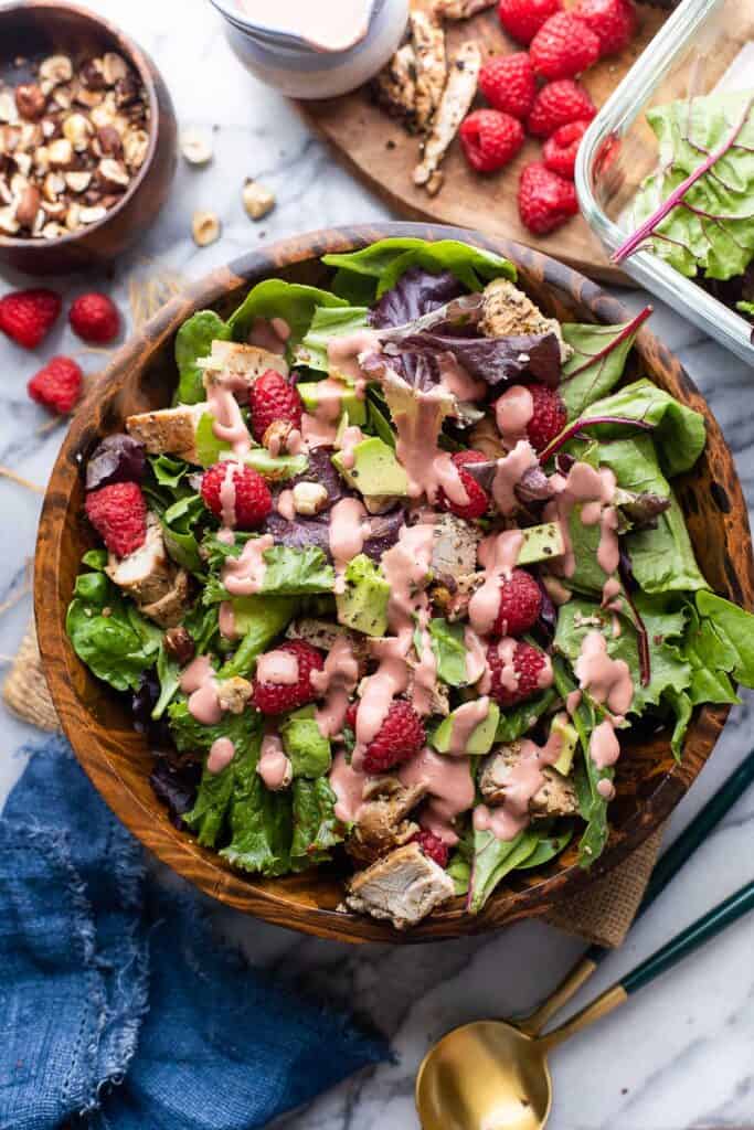 chicken-raspberry-salad in a wooden salad bowl with a creamy raspberry dressing on top