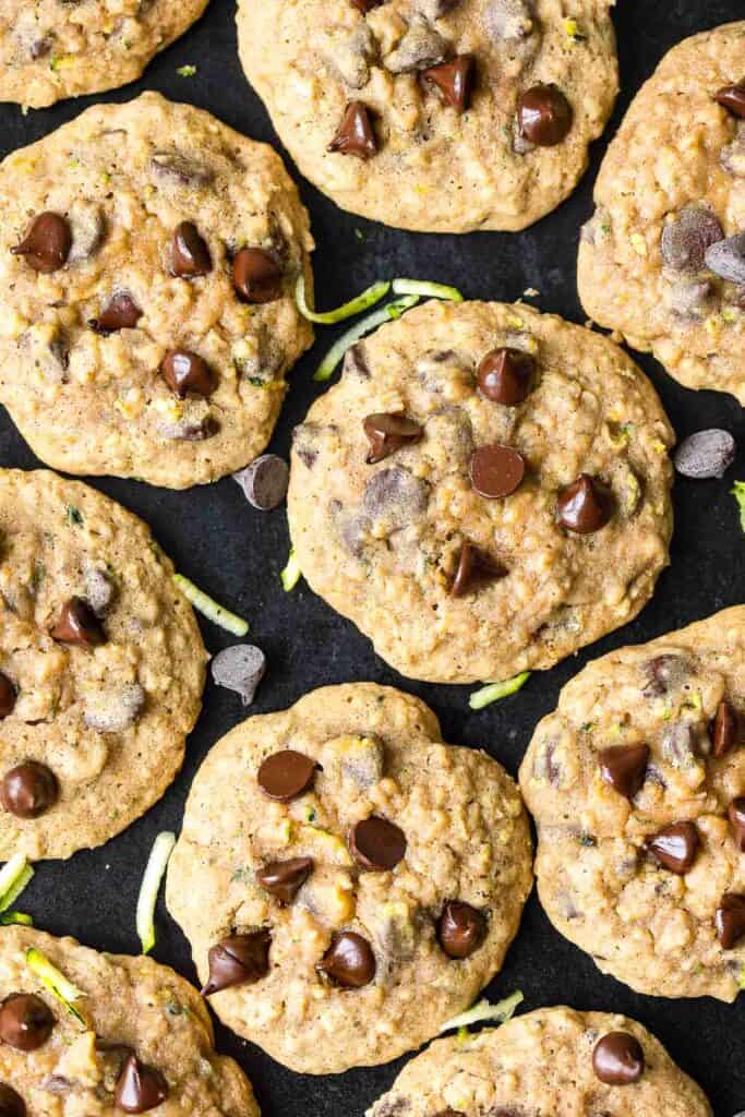 Chocolate Chip Zucchini Oatmeal Cookies on a baking sheet with shredded zucchini bits and chocolate chips around the cookies