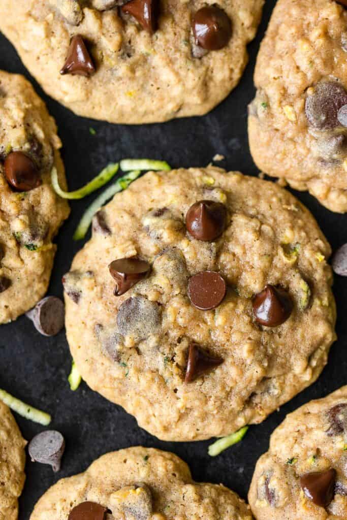 a Zucchini Oatmeal Cookies on a baking sheet with fresh zucchini and chocolate chips